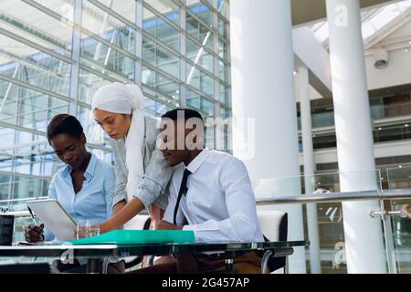 Male and females executives discussing over digital tablet at desk Stock Photo