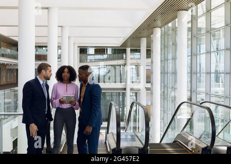 Young business talking on the escalator in modern office building Stock Photo