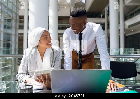 Male and female executives discussing over digital tablet at desk Stock Photo