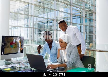 Male and females executives discussing over laptop at desk Stock Photo