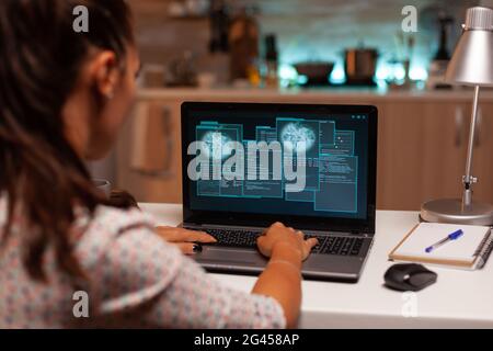 Female hacer cracking security firewall late at night from home. Programmer writing a dangerous malware for cyber attacks using performance laptop during midnight. Stock Photo
