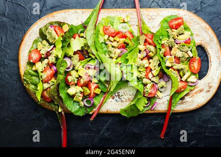 Salad with tomato,avocado,garlic sauce in chard leaves.Summer vitamin salad on kitchen board Stock Photo