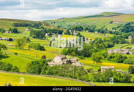 The colourful hay meadows in Summer with bright yellow buttercups in the pretty hamlet of Langthwaite, Arkengarthdale in the Yorkshire Dales, UK.  Hor Stock Photo