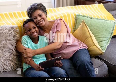 Mixed race boy and his grandmother Using digital tablet sitting on a couch Stock Photo
