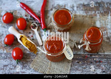 Homemade Curry Sauce. Jars with curry sauce, tomatoes, seasonings. Stock Photo