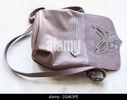 open empty handcrafted leather cross body bag with butterfly applique on concrete board Stock Photo