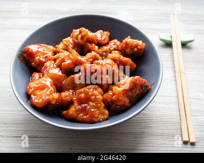 chinese cuisine - sweet and sour pork (guo bao rou) in gray bowl on wooden table Stock Photo