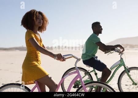 Mixed race couple riding bikes on the beach Stock Photo