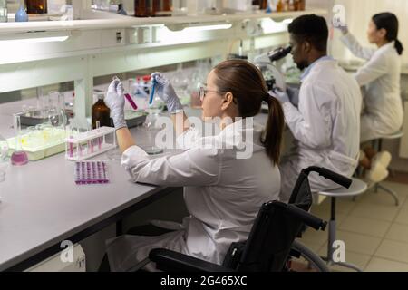 Group of intercultural lab workers sitting in row during scientific experiments Stock Photo