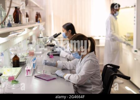 Group of contemporary scientists in whitecoats working in lab Stock Photo
