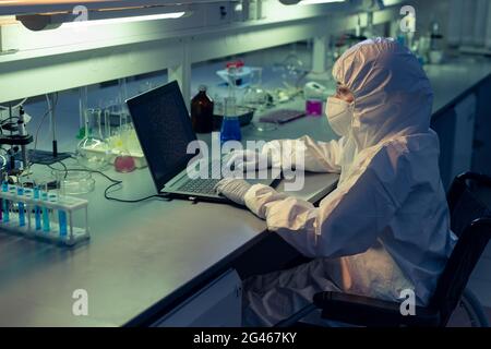 Female researcher in wheelchair looking at laptop display while working in scientific laboratory Stock Photo
