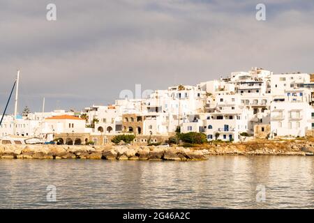 Naoussa coastal village (Paros Island) landscape view during golden hour with typical whitewashed cycladic houses and dramatic sky seen from the sea, Stock Photo