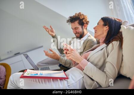 A young business couple enjoying a nice talk on the couch in a relaxed atmosphere in an apartment after hard working day. Business, couple, leisure, t Stock Photo