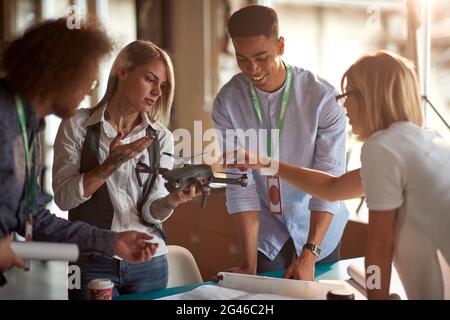 A group of young creative people in a working atmosphere in the office discuss the drone they will use in the project. Employees, office, work Stock Photo