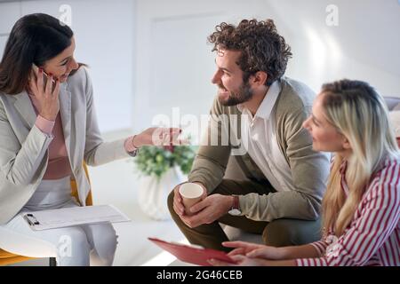 A group of young business people in a relaxed atmosphere at a meeting having a nice talk at a break. People, business, meeting Stock Photo