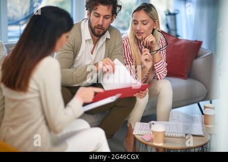 A group of young business people at a meeting in a relaxed atmosphere review some important data from documents. People, business, meeting Stock Photo