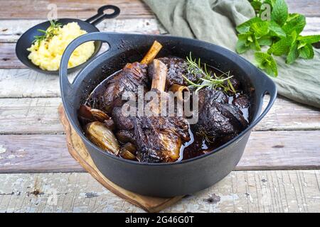 Modern style traditional braised slow cooked lamb shank in red wine sauce with shallots and mashed potatoes offered as close-up Stock Photo