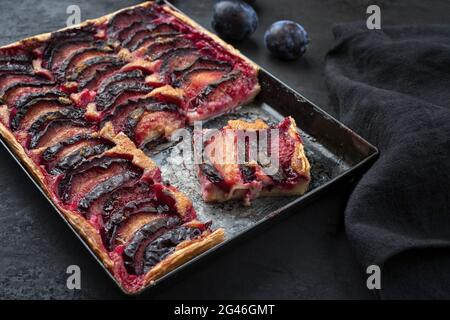 Traditional French tarte aux prunes with sweet plums and vanilla offered as closeup on a rustic metal tray Stock Photo