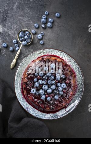 Traditional French tarte aux myrtilles with sweet blueberries and vanilla offered as top view on a design plate with rustic blac Stock Photo