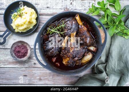 Modern style traditional braised slow cooked lamb shank in red wine sauce with shallots and mashed potatoes offered as top view Stock Photo