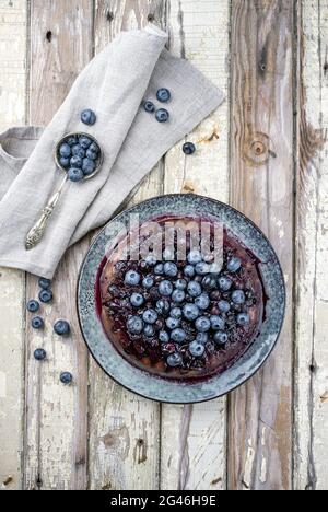 Traditional French tarte aux myrtilles with sweet blueberries and vanilla offered as top view on a design plate with rustic wood Stock Photo