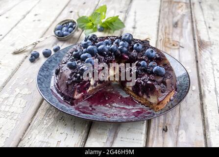 Traditional French tarte aux myrtilles with sweet blueberries and vanilla offered as close-up on a design plate with rustic wood Stock Photo