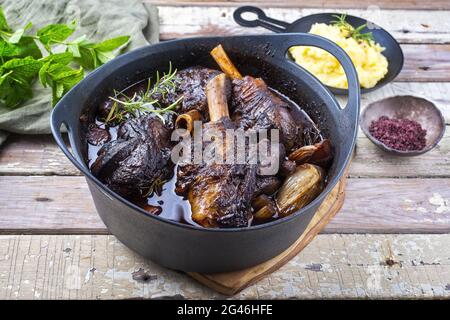 Modern style traditional braised slow cooked lamb shank in red wine sauce with shallots and mashed potatoes offered as top view Stock Photo