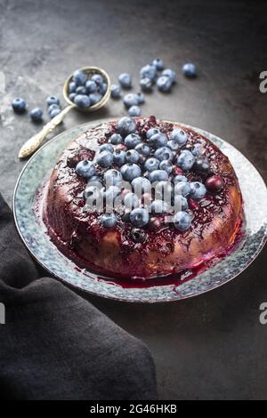 Traditional French tarte aux myrtilles with sweet blueberries and vanilla offered as close-up on a design plate with rustic blac Stock Photo