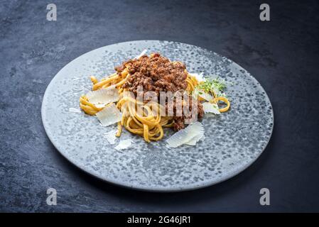 Modern style traditional Italian ragu alla bolognese sauce with linguine pasta noodles and parmesan cheese served as close-up in Stock Photo