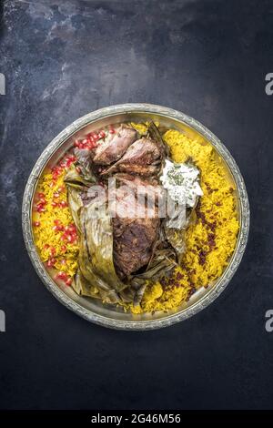 Slow cooked Omani lamb shuwa coated in rub of spices and wrapped in banana leaves served with rice and yoghurt as top view on a Stock Photo