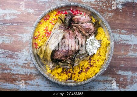 Slow cooked Omani lamb shuwa coated in rub of spices and wrapped in banana leaves served with rice and yoghurt as top view on a Stock Photo
