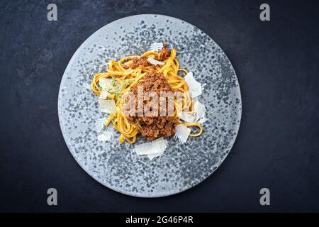 Modern style traditional Italian ragu alla bolognese sauce with linguine pasta noodles and parmesan cheese served as top view in Stock Photo