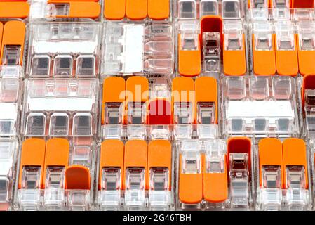 Background made of multiple couplers for strands and solid conductors for electric cables, with a few open levers. Stock Photo