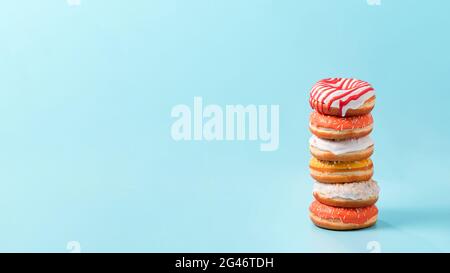 Stack of donuts on blue background with copy space Stock Photo