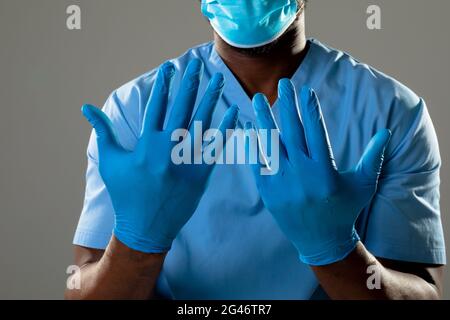 Mid section of african american male health worker wearing surgical gloves against grey background Stock Photo