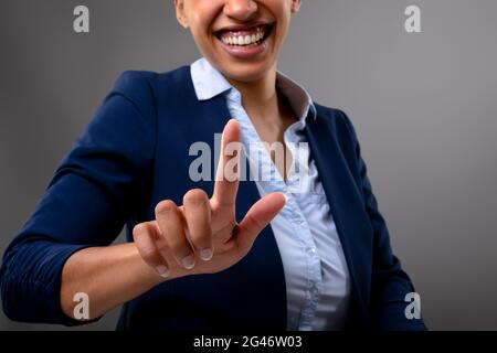 Mid section of african american businesswoman touching invisible screen against grey background Stock Photo