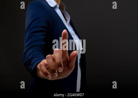 Mid section of businesswoman touching touching invisible screen against black background Stock Photo