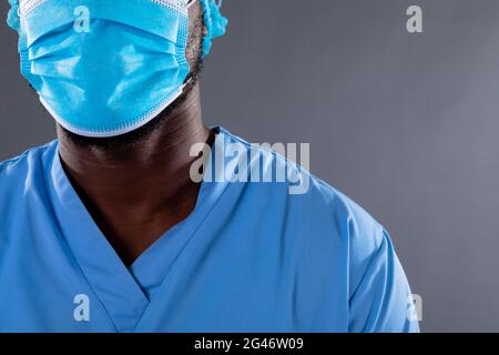 Mid section of african american male health worker wearing face mask against grey background Stock Photo