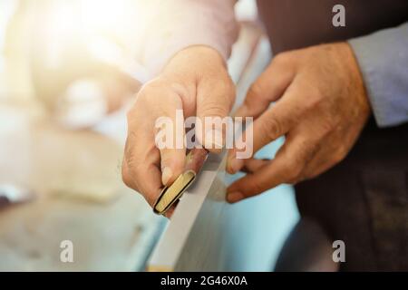 The hands of an elderly carpenter and a tool while working in close-up. Stock Photo