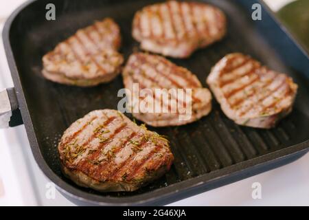 Four toasted steaks on a grilled pan, with finely chopped rosemary. Stock Photo