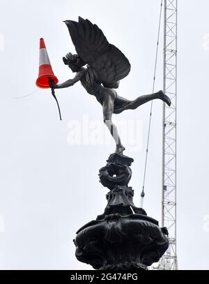 Piccadilly Circus, London, UK. 19th June 2021. A traffic cone on the bow of the Eros statue in Piccadilly Circus. Credit: Matthew Chattle/Alamy Live New Stock Photo