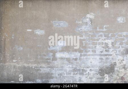Front view of an old, dirty, damaged&plastered wall. Plaster is partly peeled off revealing old bricks. High resolution full frame textured background Stock Photo