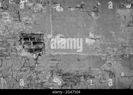 Front view of an old, dirty, damaged&plastered wall. Plaster is partly peeled off revealing old bricks. High resolution full frame textured background Stock Photo