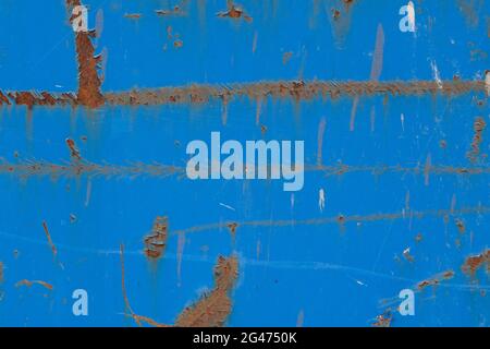 Close-up of a weathered sheet metal plate painted in blue. Paint is partly peeled off revealing rusty metal. Full frame abstract background. Stock Photo