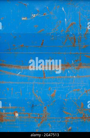 Close-up of a weathered sheet metal plate painted in blue. Paint is partly peeled off revealing rusty metal. Full frame abstract background. Stock Photo