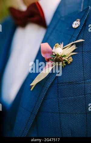 The groom's budier of yellow flowers on a checkered jacket and a red bow tie. Stock Photo