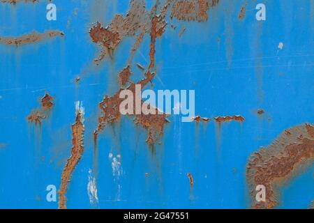 Close-up of a weathered sheet metal plate painted in blue. Paint is partly peeled off revealing rusty metal. Full frame abstract background. Stock Photo