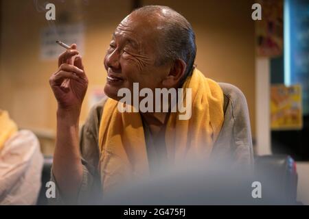 Portrait of an old Japanese man smoking indoors in Tokyo Stock Photo