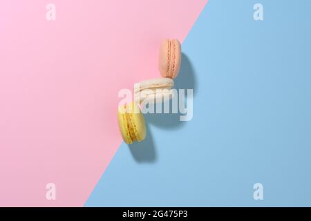Round multicolored macarons on a pink-blue background with a shadow. Gourmet almond flour dessert Stock Photo