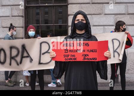 Dublin, Ireland. 19th June, 2021. Ana Paula from Brazil holds a placard during the demonstration.Protesters gathered at the Spire to demonstrate against the Brazilian President Jair Bolsonaro. Protesters demanded a better distribution of Covid-19 vaccines in Brazil, as well as action on the country's recent increase in hunger and Bolsonaro's impeachment. Credit: SOPA Images Limited/Alamy Live News Stock Photo